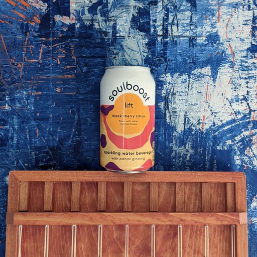A lifestyle photo of a Soulboost can against a paint textured wall